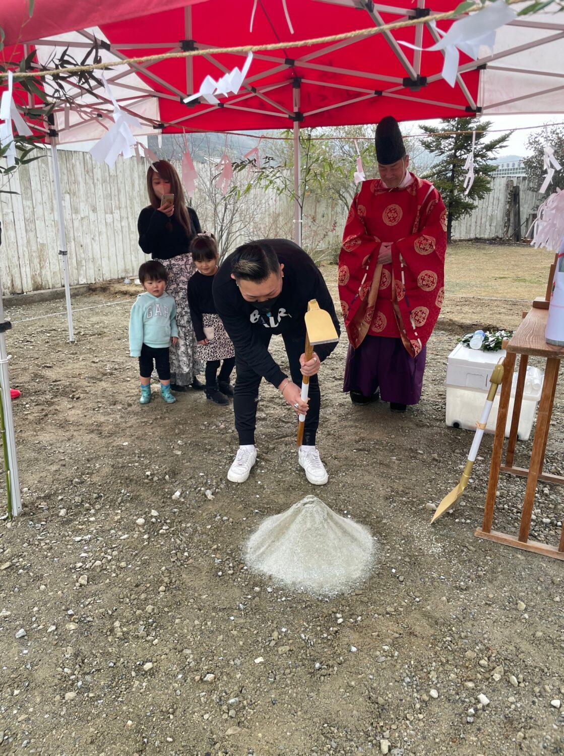 アイデザインホームの現場リポート　地鎮祭の現場リポート　広島県の工事現場　広島県で注文住宅ならアイデザインホーム　男性が盛り砂にめがけて鍬を振り下ろす様子