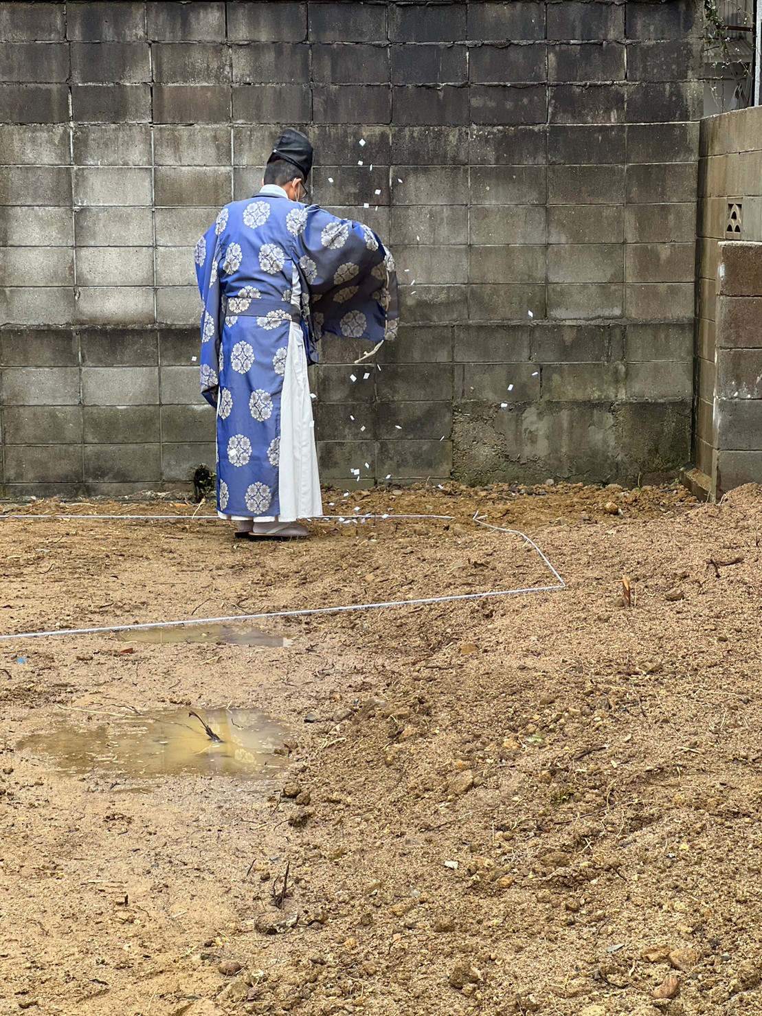 アイデザインホームの現場リポート　地鎮祭の現場リポート　兵庫県で注文住宅ならアイデザインホーム　ブロック塀の前で紙を撒く神主さん