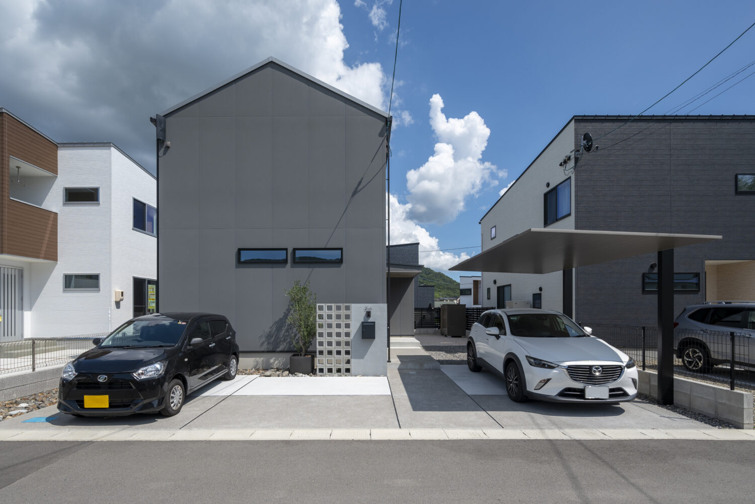 広島県の注文住宅　広島県安芸郡の建築実例　広島県で注文住宅ならアイデザインホーム　三角屋根とグレーの外壁のシンプルな家　黒と白の車が停まっているグレーの家