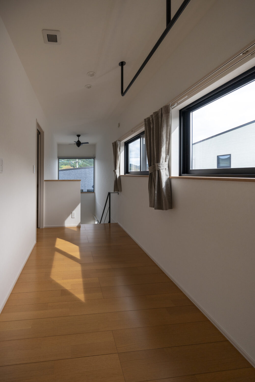 広島県の注文住宅　広島県安芸郡の建築実例　広島県で注文住宅ならアイデザインホーム　室内に物干しスペース確保した空間　ブラックのシーリングファンとアイアン物干しがある2階ホール