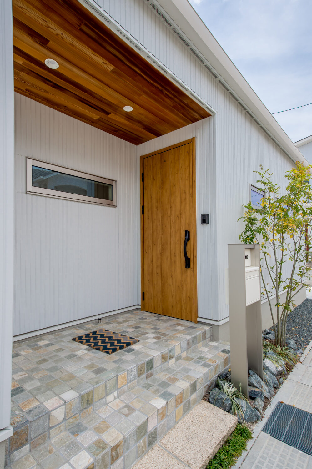 アイデザインホーム　注文住宅　広島県福山市　ホワイトの外観の中で、玄関扉と玄関ポーチ上部に木を使う事で、小気味良いアクセントになっています