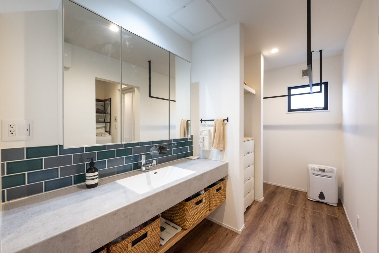 アイデザインホーム
三重の注文住宅　実例
アイカのグレーの造作洗面台をメインとした洗面室はランドリーコーナーも兼ねており、アイアンのランドリーパイプが設置してある。
収納スペースも設け、家事ラクな空間をつくっている。