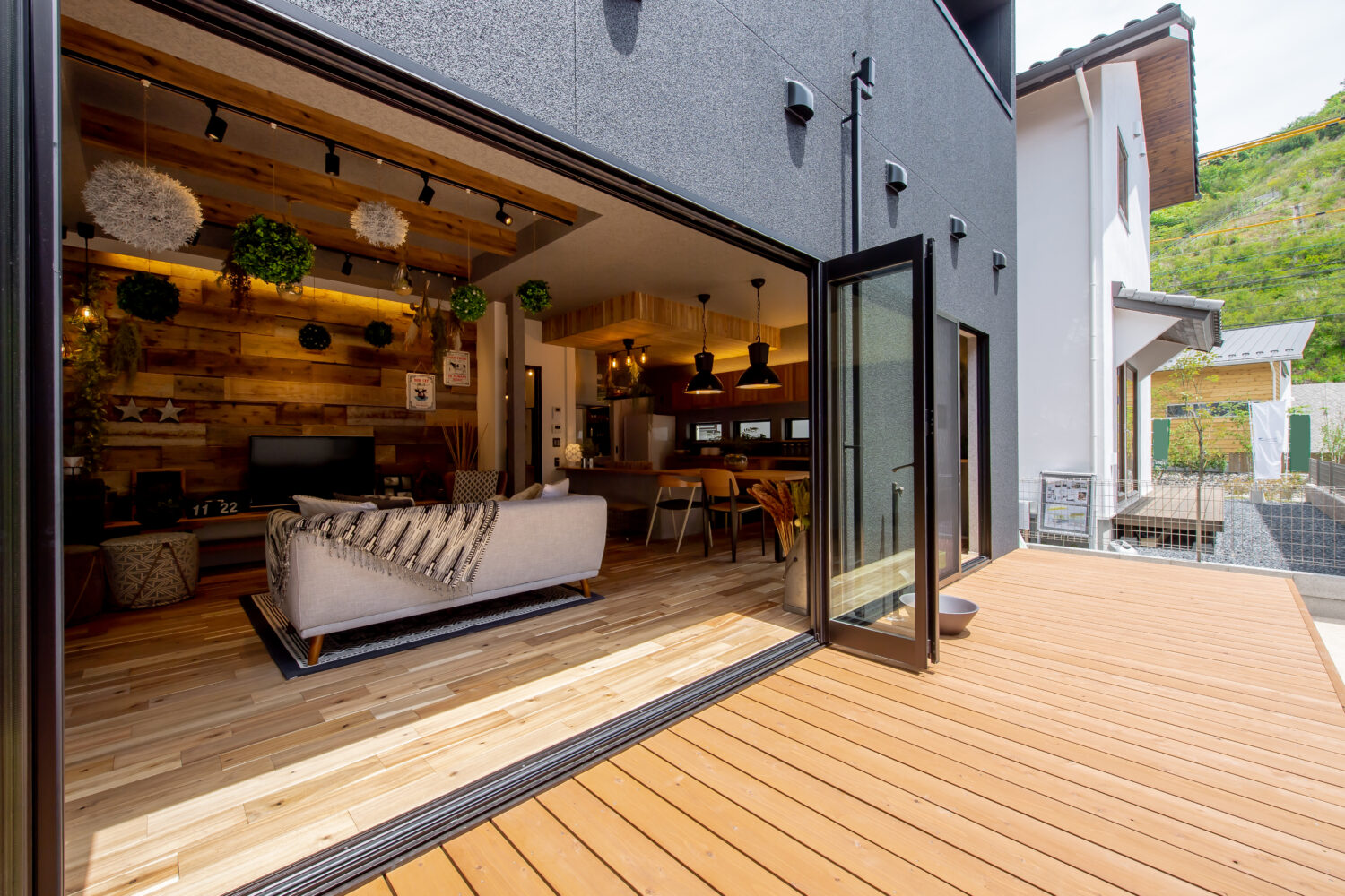 広島の注文住宅ならアイデザインホーム｜ひろびろとしたウッドデッキと全開口サッシが屋内空間を屋外に広げています。
