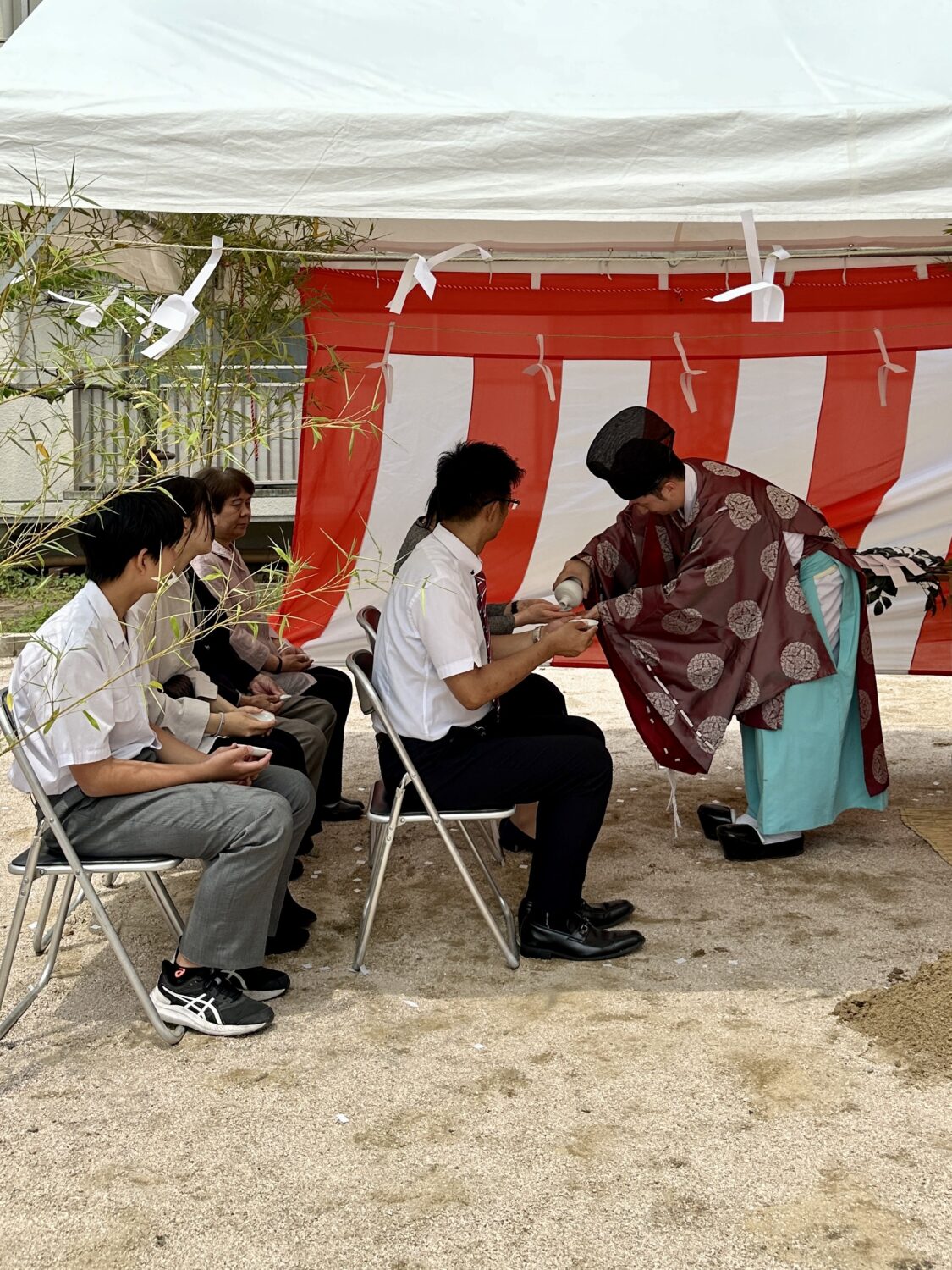 アイデザインホームの現場リポート　広島県で注文住宅ならアイデザインホーム　地鎮祭の現場リポート　神主さんがお供えで使ったお酒を振る舞う様子