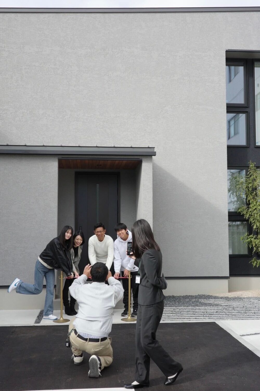 注文住宅ならアイデザインホーム　広島の注文住宅　アイデザインホームの現場リポート　お引渡しの現場リポート　テープカットを行う家族とそれを撮影している人たち
