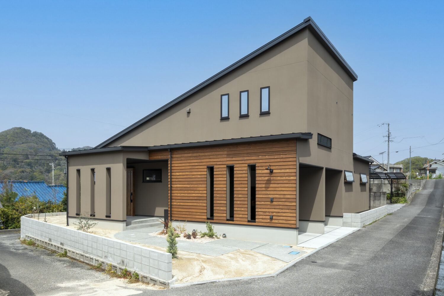 広島県で注文住宅ならアイデザインホーム　アイデザインホームの実例集　山陽エリアの注文住宅　たくさんのサンプルから選んだブラウンの外壁と板張りのアクセントを組み合わせた、大きな片流れ屋根が印象的な外観　ビルトインガレージを採用し、雨風による汚れや傷から愛車を守ることができます