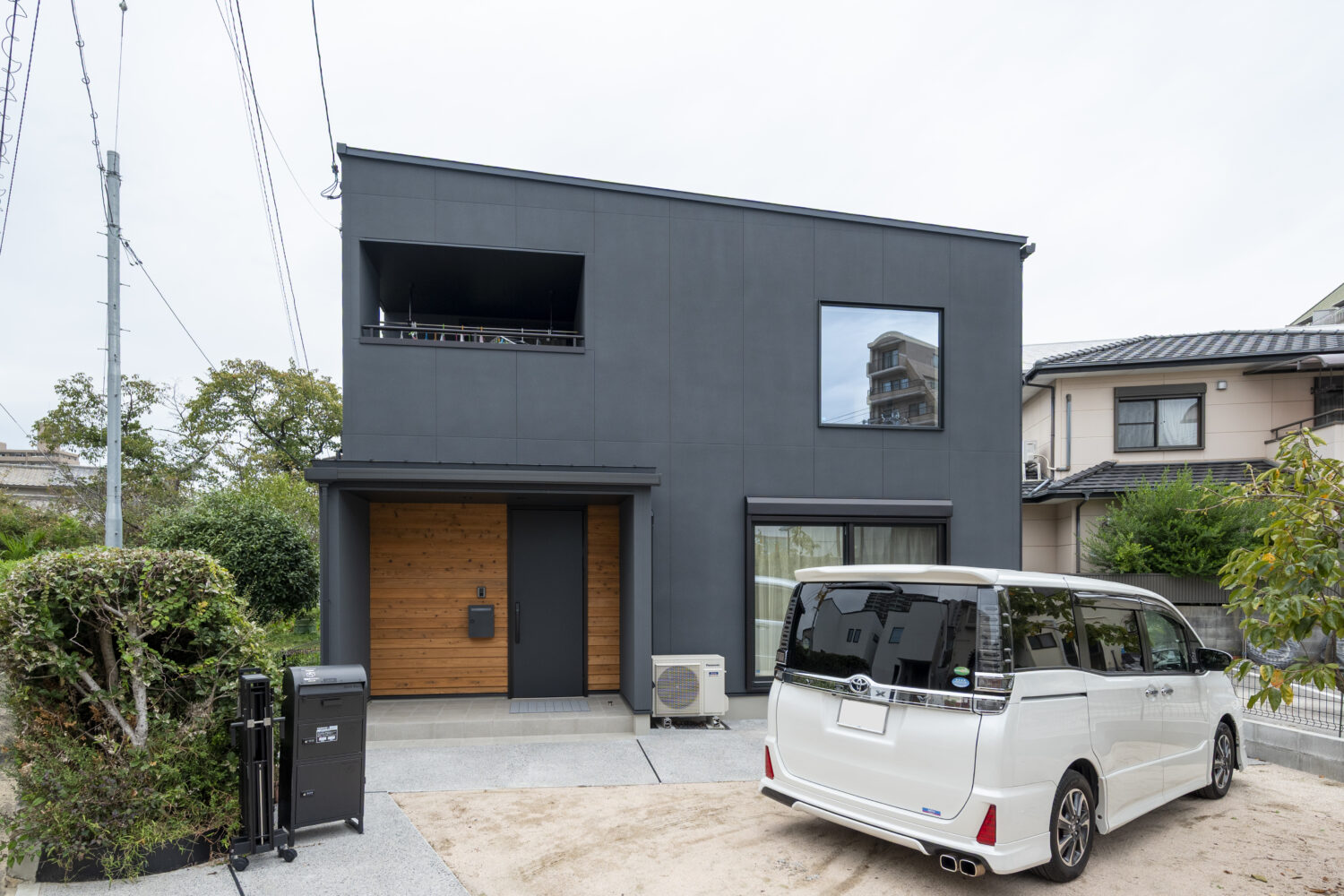 広島で注文住宅ならアイデザインホーム　アイデザインホームの実例集　開放感と住みやすさを実現！大きな吹抜と家事動線にこだわった家　ブラックの外壁を基調に、玄関部分のみアクセントとして杉板張りを採用した外観