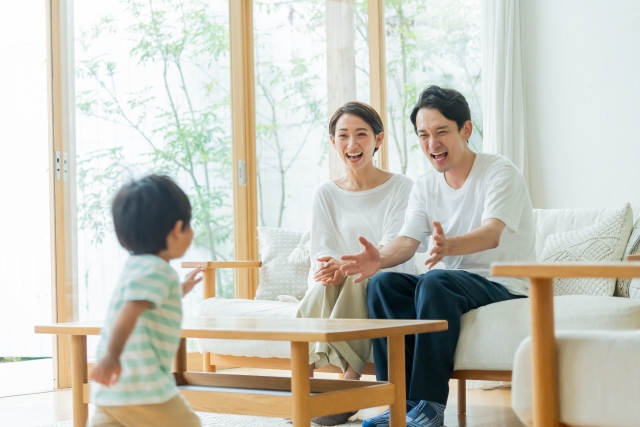気密性が暮らしに与える影響| C値0.5以下が当たり前になる理由|注文住宅ならアイデザインホーム|ソファに座る両親に駆け寄っていく子ども