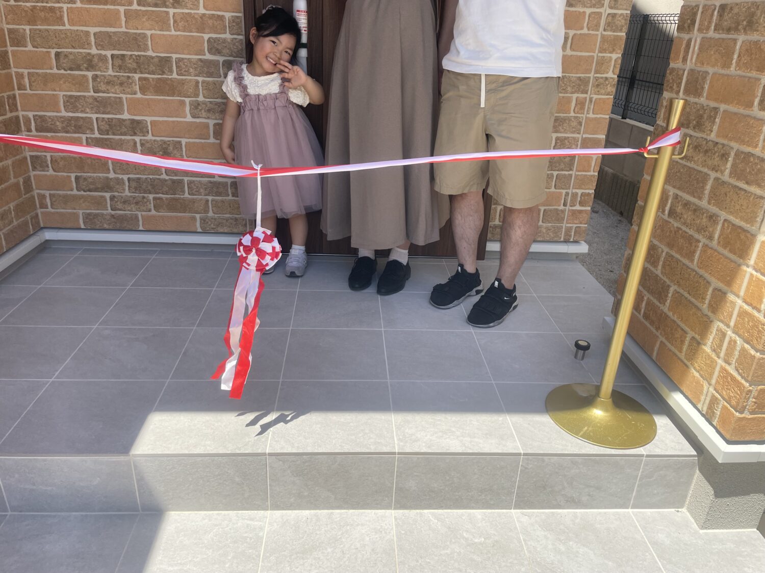 広島で注文住宅ならアイデザインホーム|引渡の現場リポート|テープカットをする前に記念撮影をする家族