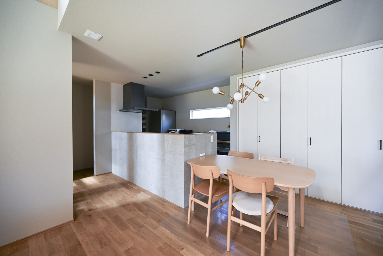 家族のこだわりが詰まった箱型ヌックと回遊動線のある家｜アイデザインホームの施工事例｜料理中の手元が隠せるよう腰壁を設けたキッチンは、セメントの風合いと調湿作用を兼ね備えたSOLIDO仕上げで、洗練された雰囲気を演出