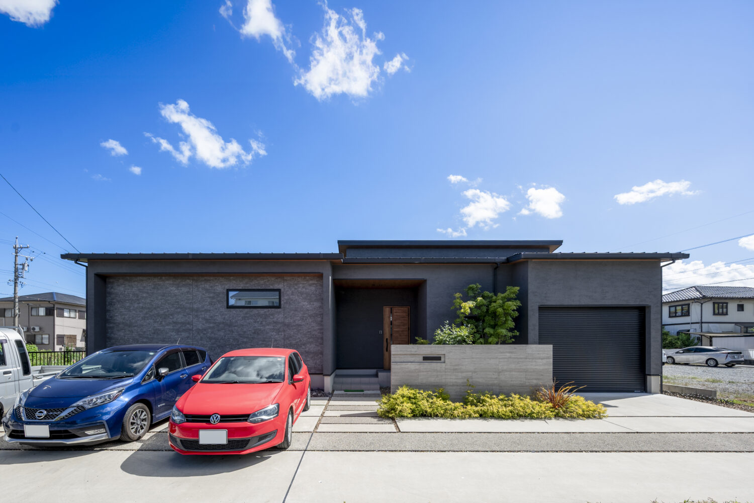 実例集(施工事例)を更新しました｜アイデザインホーム｜家族が自然に集うリビングとビルトインガレージのある平屋｜ダークトーンのグレーを基調とした落ち着きのある外観。雨風からお気に入りのヴィンテージカーを守れるよう、シャッター付きのビルドインガレージを設けています